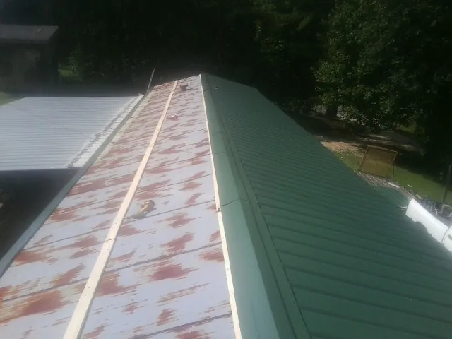 Old rusted panels beside newly installed green metal roofing — Wind Damage Roof Repair by Roofing Brothers in Mission
