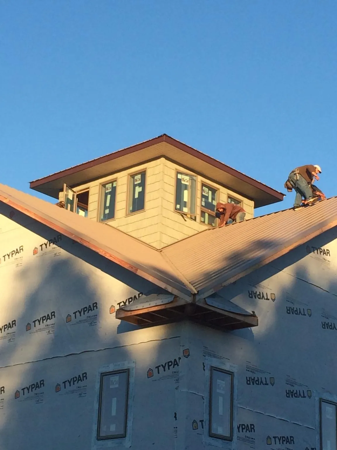 Roofers working around a rooftop cupola on a new metal roof at sunset — Roof Waterproofing in Mission by Roofing Brothers